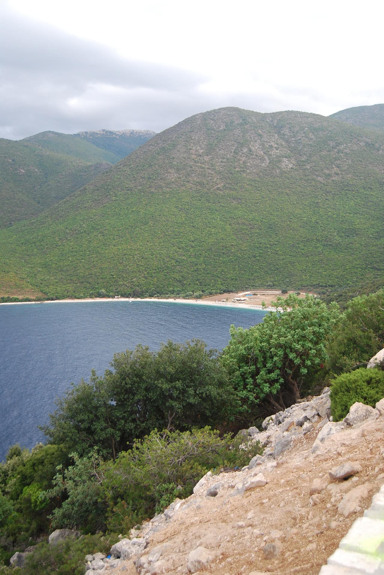 Pebble shore and clear water backed by green hills at Antisamos Beach, Kefalonia