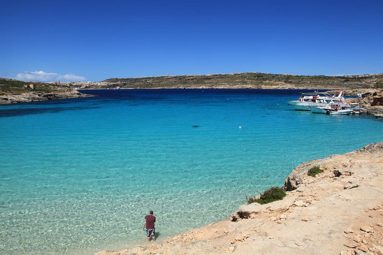 Boats moored in the shallow turquoise channel of the Blue Lagoon at Comino, Malta