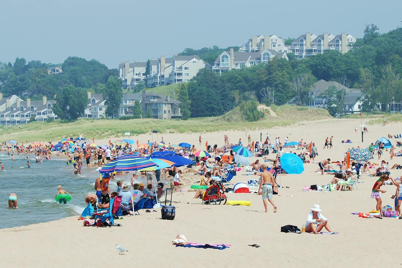 Wide sandy beach at Holland State Park on Lake Michigan with people swimming near the shoreline