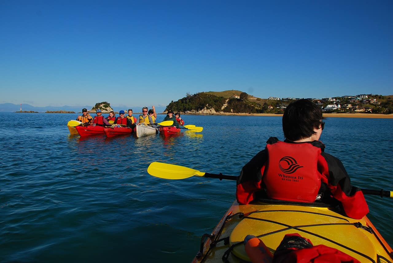 Sea kayakers paddling along a rocky coastline