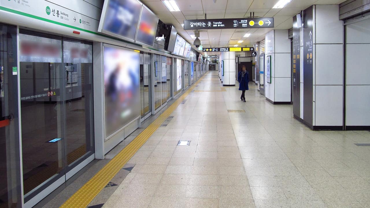A clean, tiled subway platform with screen doors on the Seoul Metro