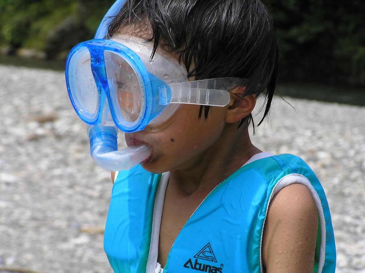 A swimming mask and a J-shaped snorkel tube laid out on a surface